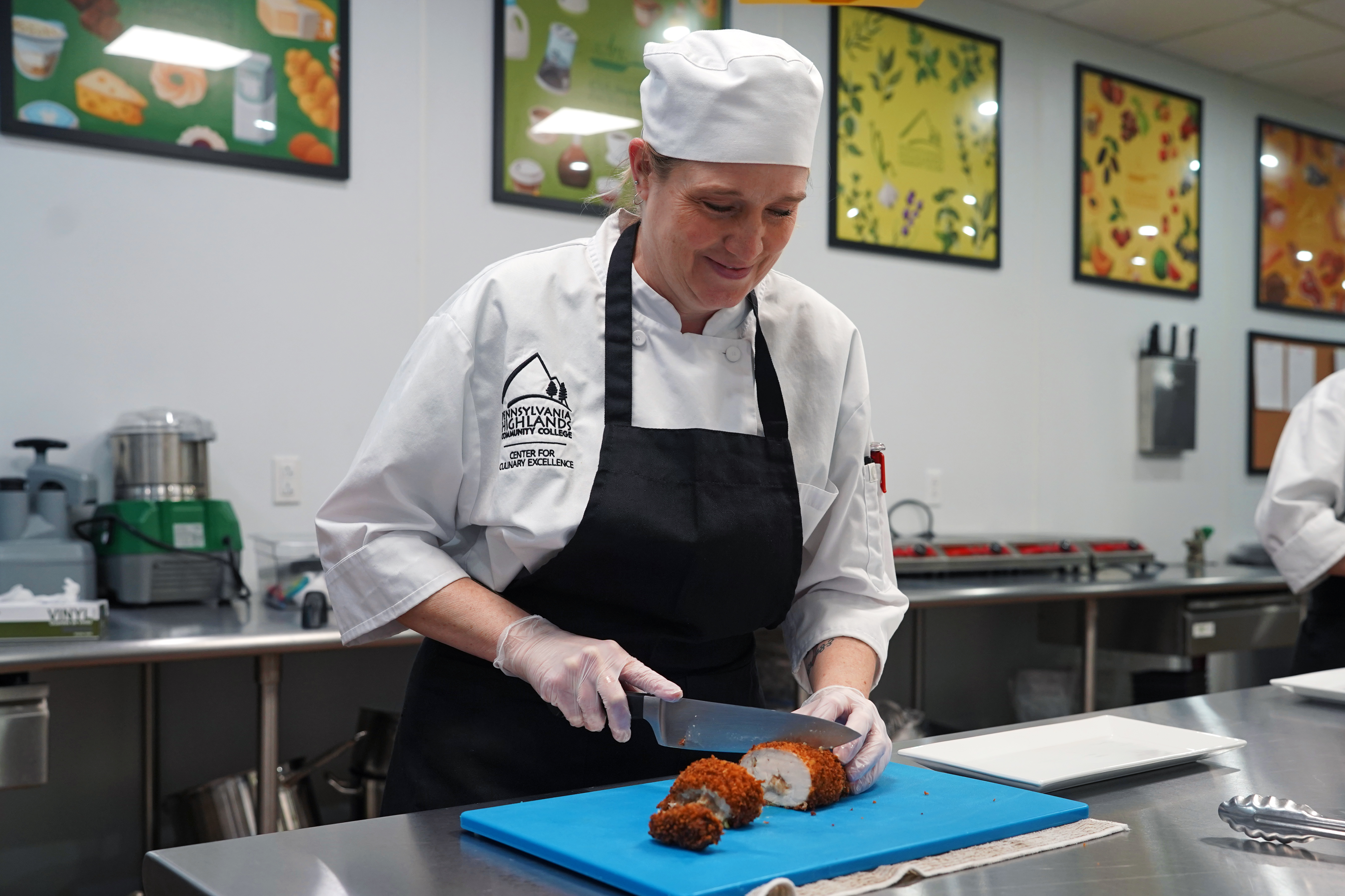 Kat Walker, chef student, cutting chicken in the culinary kitchen.