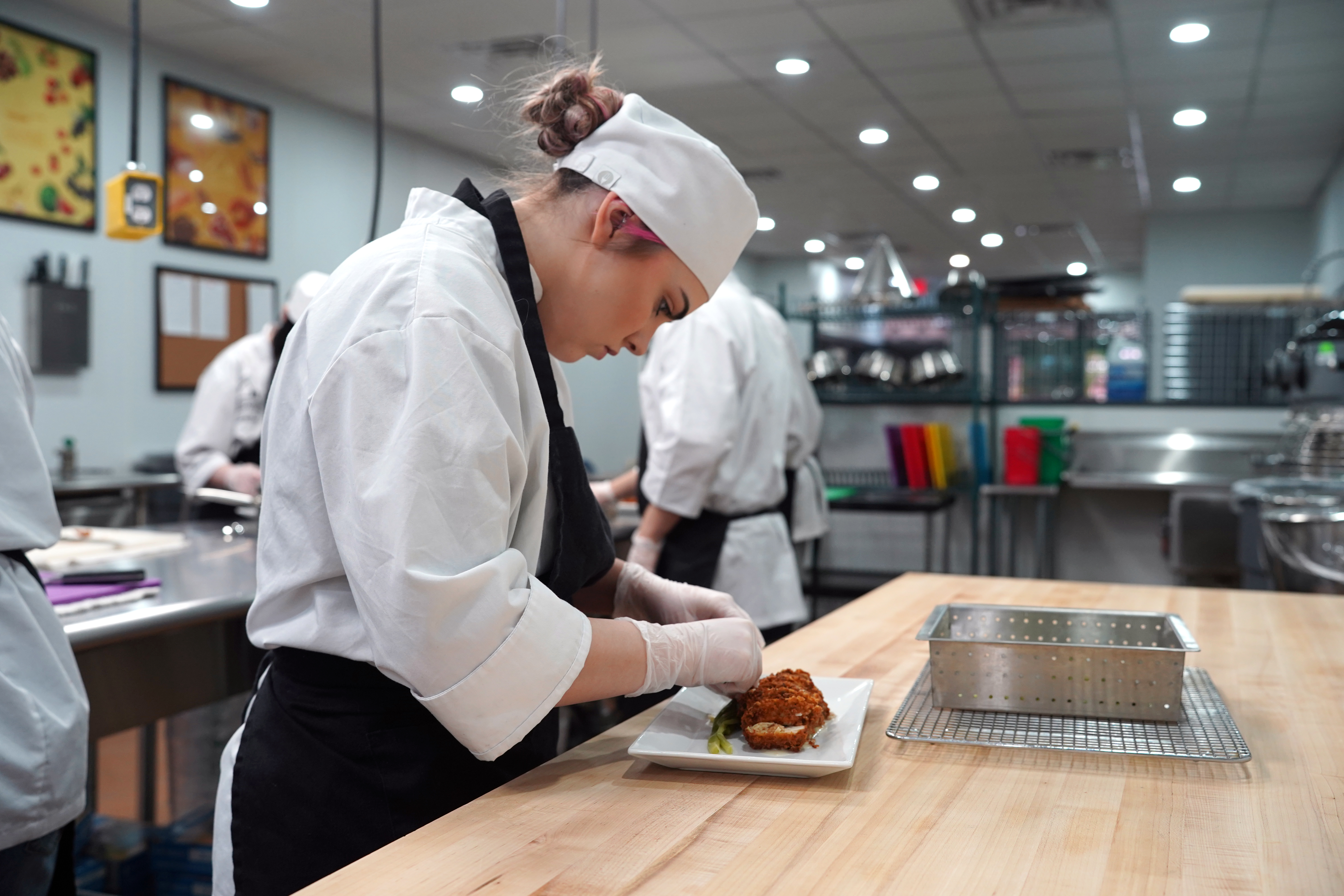 Trininty Hyatt, chef student, placing chicken in a stylish way on a plate in the culinary kitchen.