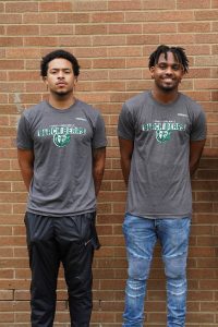 Decorative image. Two male students standing in front of a brick wall.