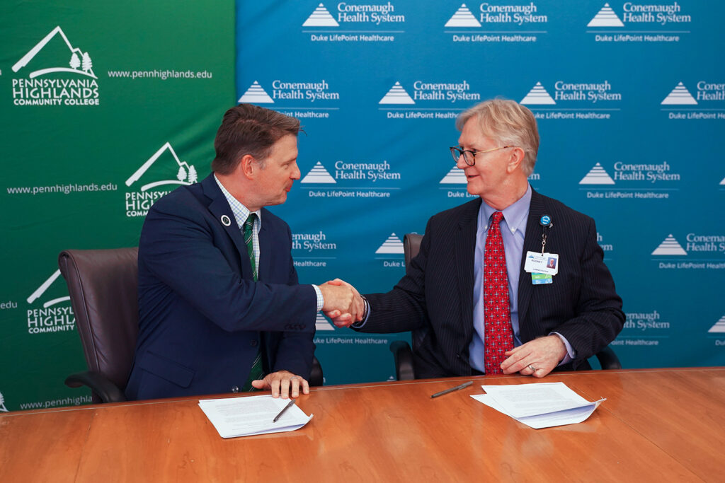 Dr. Steve Nunez (left), President of Penn Highlands Community College, shaking hands with Dr. Rodney Reider (right), CEO of Conemaugh Memorial Medical Center, after signing the Surgical Technology partnership documentation.