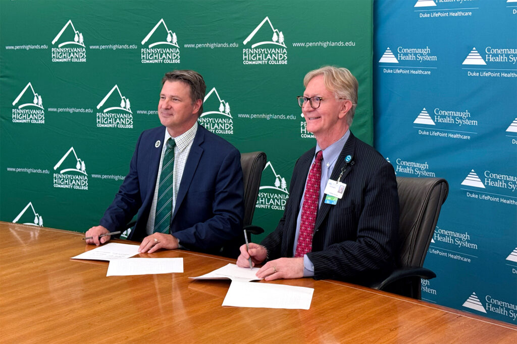 Dr. Steve Nunez (left), President of Penn Highlands Community College, sitting next to Dr. Rodney Reider (right), CEO of Conemaugh Memorial Medical Center, ready to sign Surgical Technology partnership documentation.