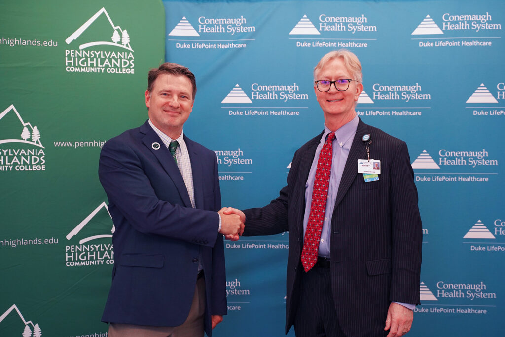 Dr. Steve Nunez (left), President of Penn Highlands Community College, shaking hands with Dr. Rodney Reider (right), CEO of Conemaugh Memorial Medical Center, after signing the Surgical Technology partnership documentation.