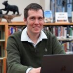 Posed photo of Matt Knepper sitting at a desk with his laptop.