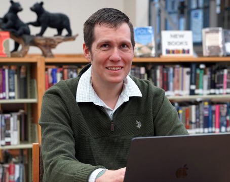 Posed photo of Matt Knepper sitting at a desk with his laptop.